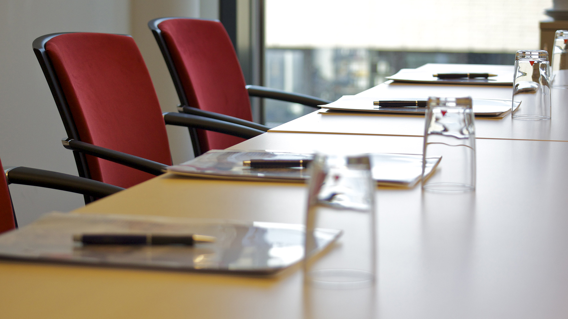 Konferenztisch mit Konferenzmappen, Stiften und Gläsern